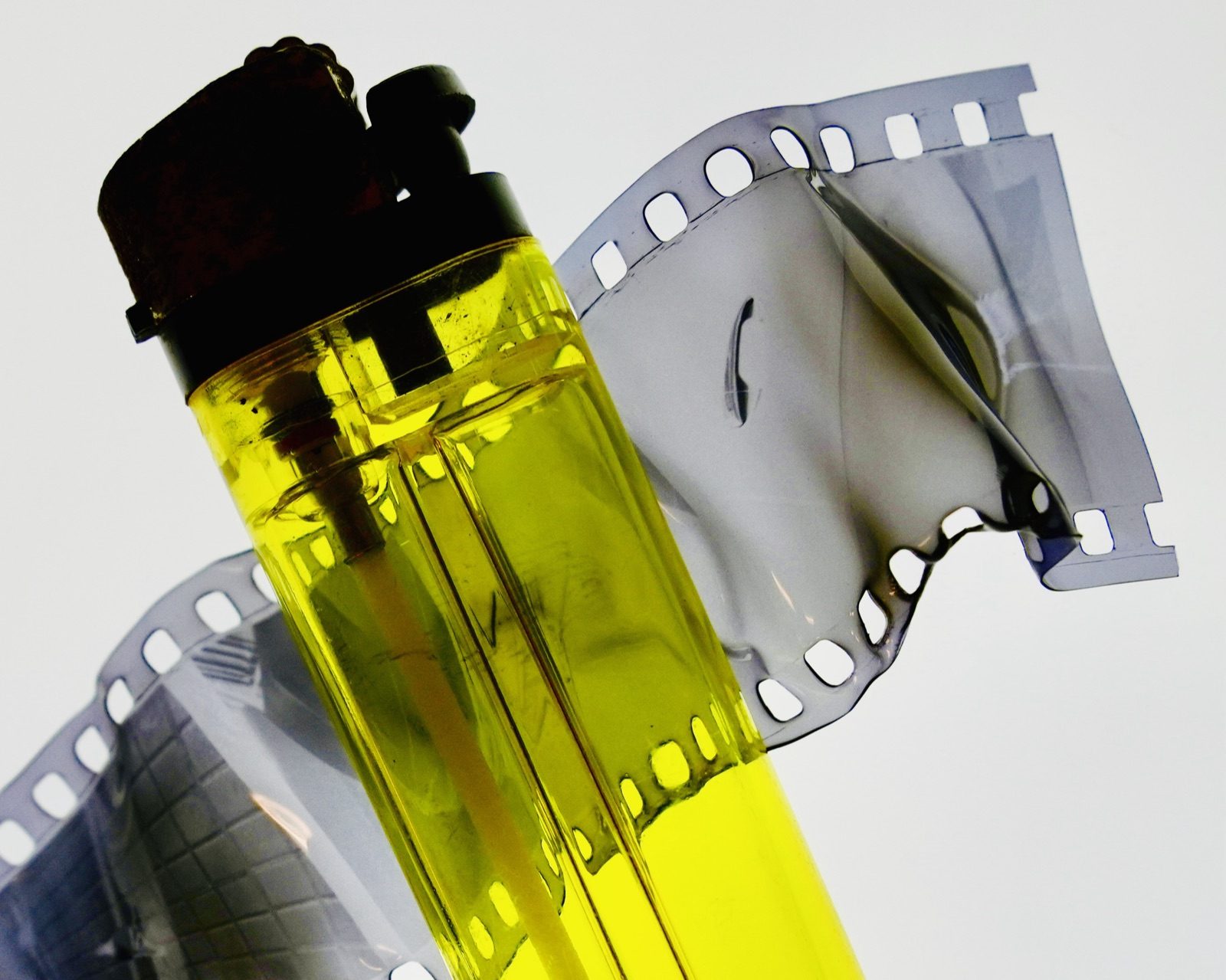 Tira de película y bote de revelado con químicos de colores en el taller de ampliación experimental